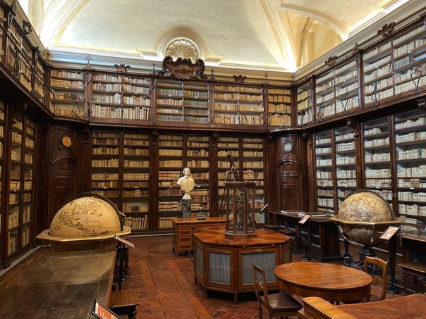 biblioteca-lancisiana-libri-mappamondo-scaffali-tavolo-books-clessidra-busto